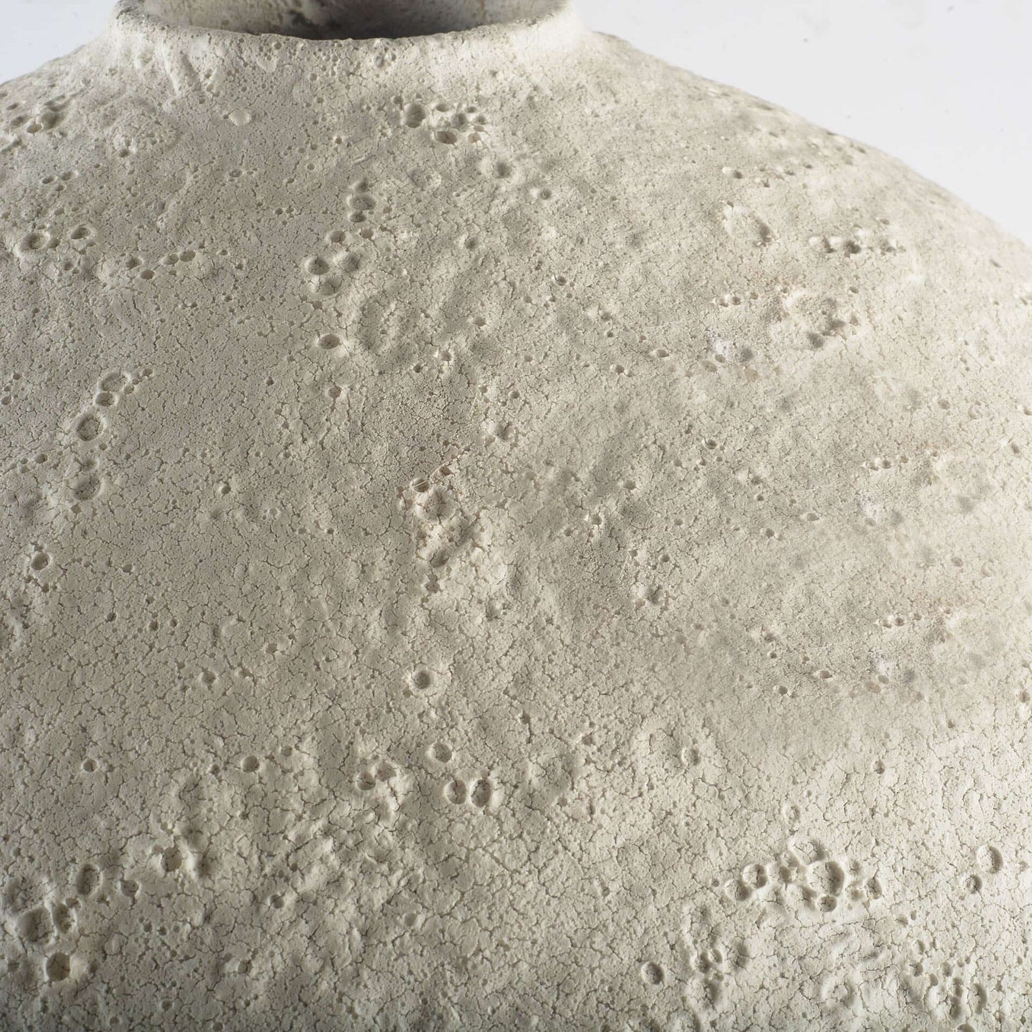 Close-up of a textured surface on a narrow white ceramic vase.